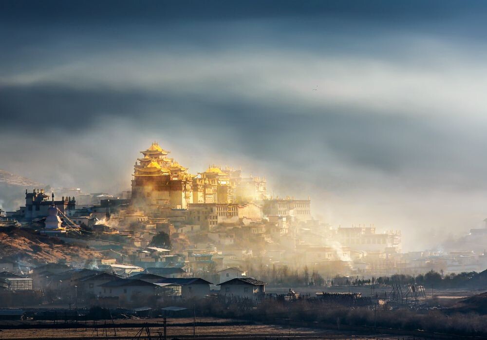 清晨的阳光照在晨雾笼罩的松赞林寺的金顶上，更金碧辉煌，如天庭圣境