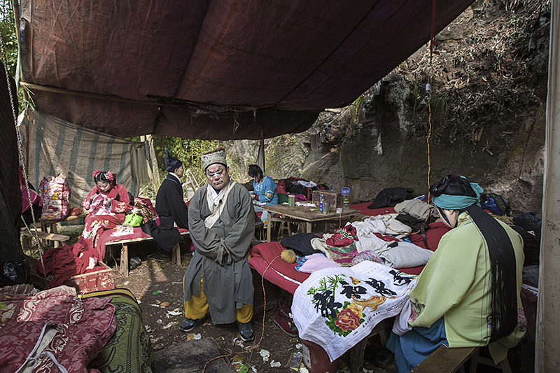 10 他们的舞台，就是由几块编织布简易围搭而成，十个演员的吃住都在这窄小的空间里。候场时演员们都忙着做十字绣。（2014年3月11日）