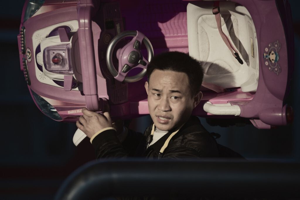 一名父亲托着一部新买的玩具车，给家里的孩子送上一份珍贵的新年礼物