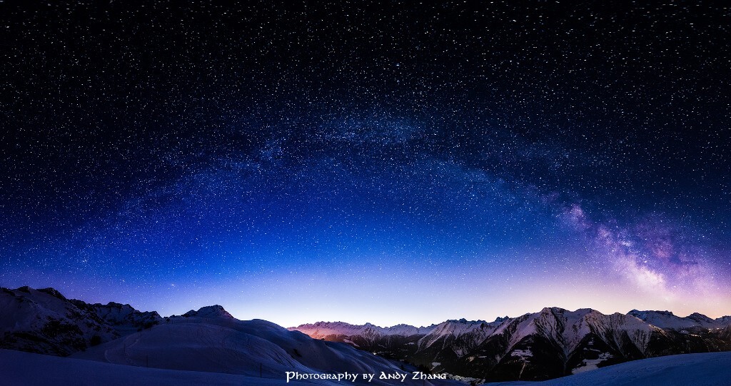 《阿尔卑斯山银河拱桥》<br />
2013年是印象中第一次看到银河，在新疆，没有任何拍摄经验，照片也就无法见人。但拍银河的心愿至此埋下了种子，不断从网上学习拍摄技巧作准备。从挪威追完极光回来之后，拍一次银河就成了下一个目标。在瑞士的阿尔卑斯山，前后花了两个周末，第一周试拍，踩点到第二周最终确定时间和机位。凌晨2点起床，零下5度，徒步一小时到雪山顶，等月落，终于迎来了最亮的漫天繁星。在日出之前的黎明时分，拍到了这张阿尔卑斯山的银河拱桥。然后伴着黎明的微光，再徒步一小时回酒店取暖。