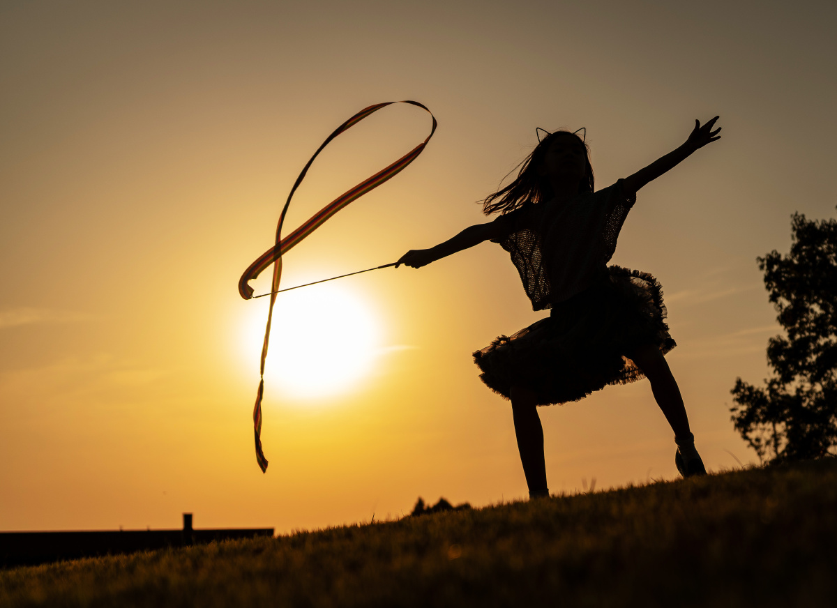 小女孩在夕阳中舞动飘带,每一个瞬间都那么美.