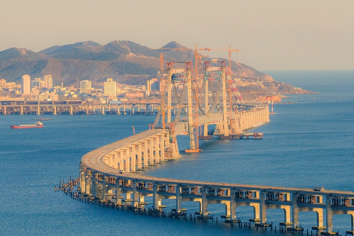大连南部滨海大道跨海大桥全长约6公里,主桥820米,其中主桥主跨460米,两侧边跨各180米。是东北地区最长的跨海大桥工程,中国首座海上地锚悬索式跨海大桥。大桥东起大连金沙滩东侧的金银山,向西跨越星海湾,在高新园区填海区域登陆,建成后将成为大连市“七纵七横”道路网中的重要一横。