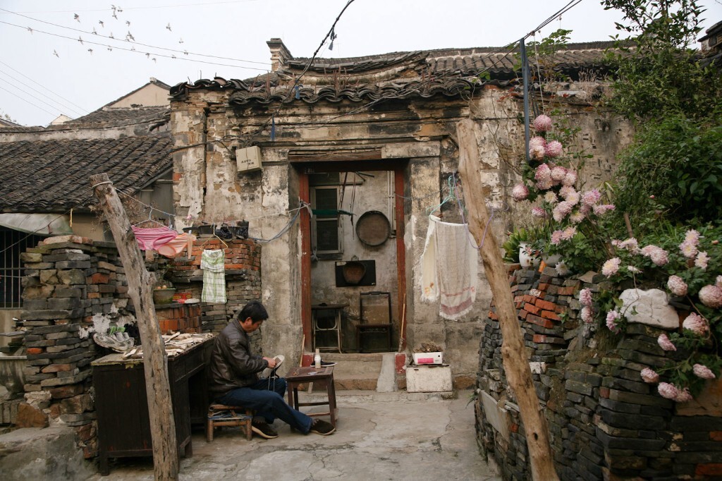 2009年12月1日,江苏无锡大窑路,一位男人在家门前为妻子补老布鞋。