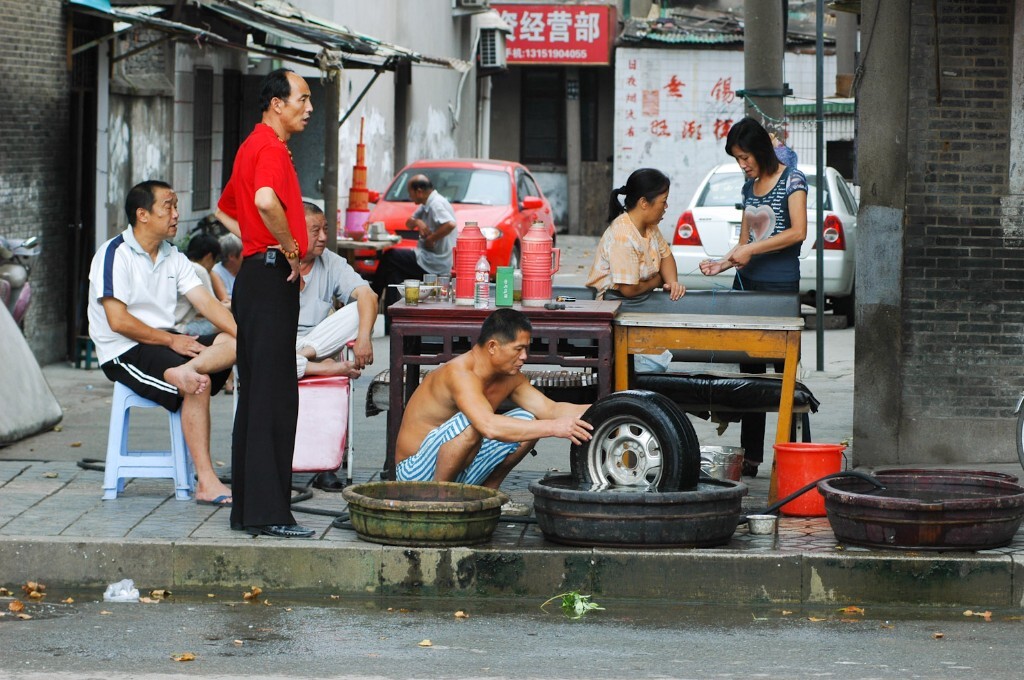 2008年9月14日,无锡唐巷,在路边用木盘补胎的居民。城市不断扩张,城村交汇,逐渐改变着弄堂人的生活方式。