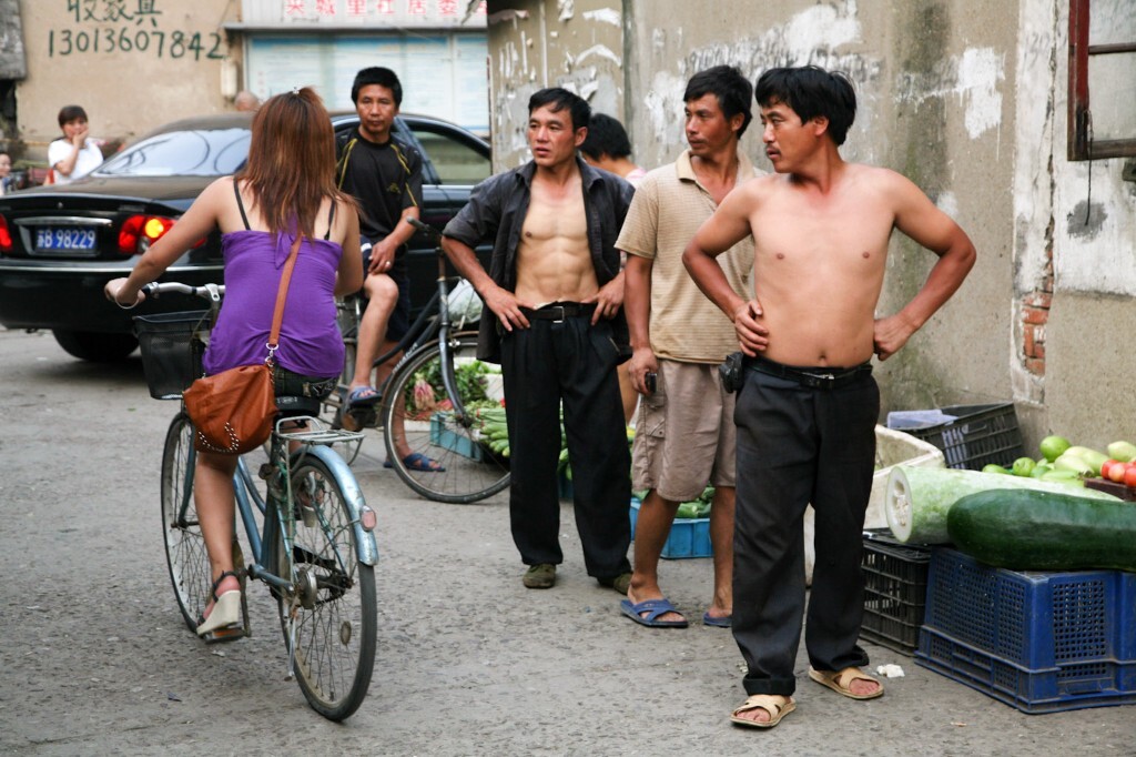 2010年7月7日,无锡夹城里,几位下班的民工盯着骑车经过的女孩看。