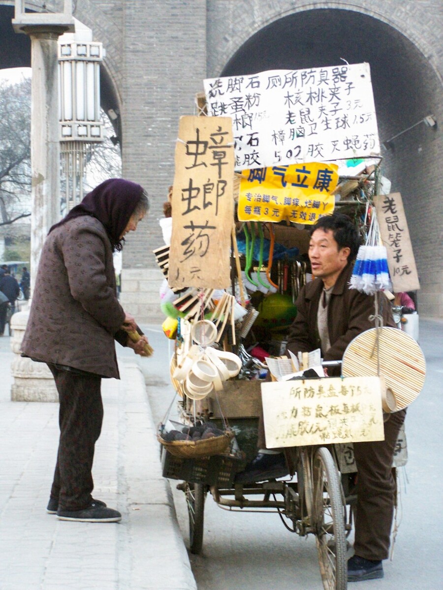 2005年12月24日,西安城墙下,一位老人与流动小贩在聊天。