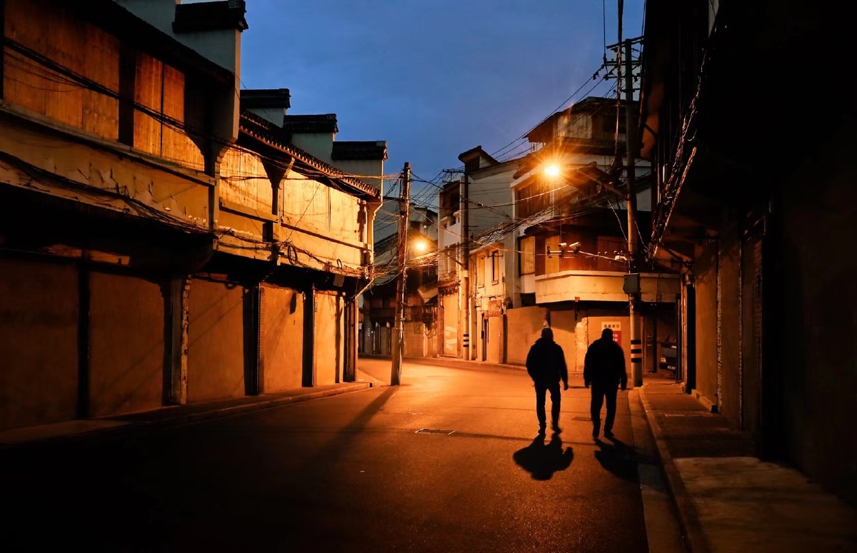 夜晚两个孤独的背影与即将拆除的老房子一起让人想到城市潮流中有些