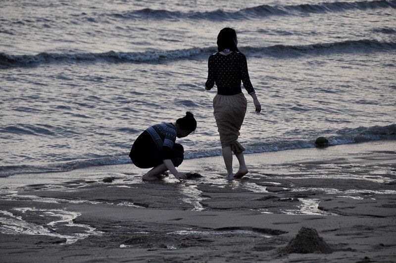 捡贝壳的女生<br />
傍晚的海边是一个无限舒服的场景。情侣散步看着舒服，小孩嬉戏看起来舒服，女孩在捡贝壳看着也舒服。有四个像我一样大的男生居然围在一起玩沙堆。有调皮的孩子围着其他摆设走来走去，他的父母在后面跟着绕来绕去，哈哈，我想我小时候也差不多这样。还有一个矮矮的小男孩低着头摆弄着什么，背后是走远了的卖冰糖葫芦的阿姨。