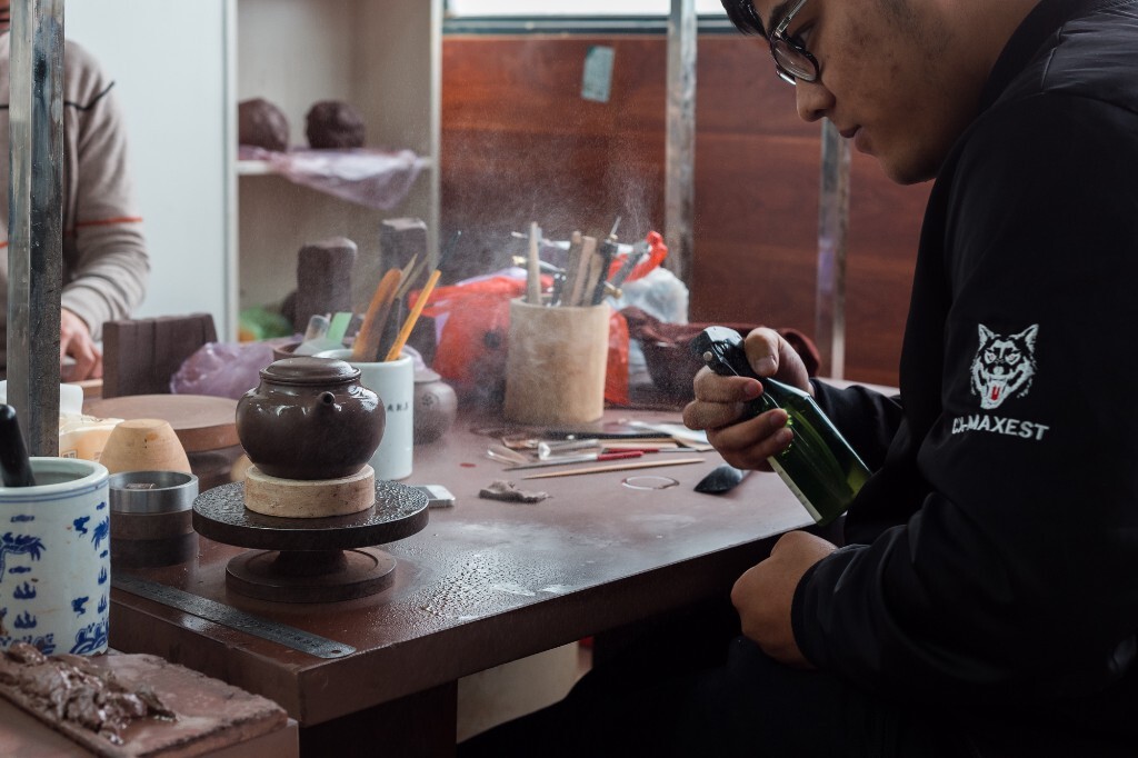 图片拍摄于2017年4月11日,云松堂工作室。紫砂艺人在向壶体喷水,以保持壶体湿润,方便后期修整。