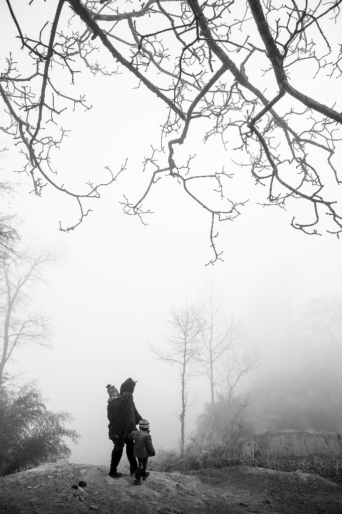 清晨,带小孩的妇人在浓雾中徘徊。