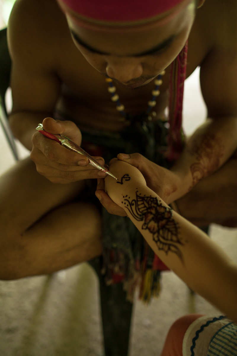 在马来民族村里,这位跳舞的小伙子弄花了小女孩的手绘纹身,随手操起