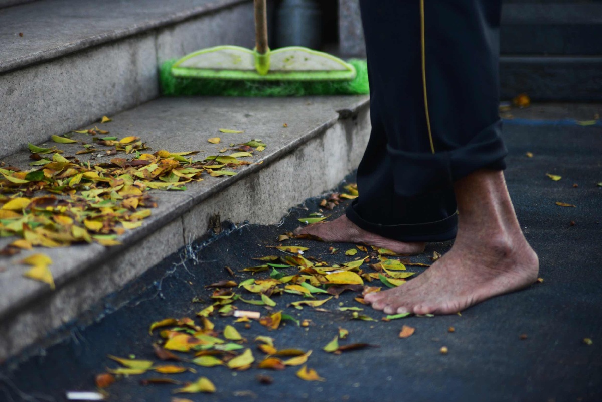 老人赤足扫落叶