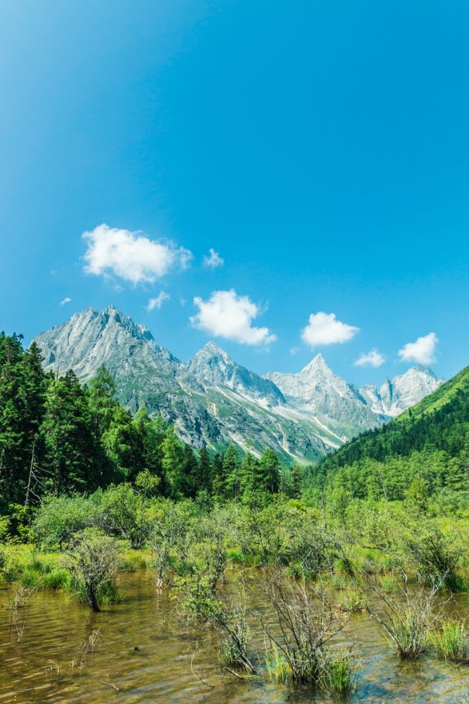 去年在四川理县毕棚沟旅游时，运气非常好，遇上一个大晴天。记得当时走到这座山前面时，云朵一直在山峰顶上形成。没想到在有个时刻刚好每座山峰的顶上都形成了一朵云，于是赶紧记录下了这一刻。