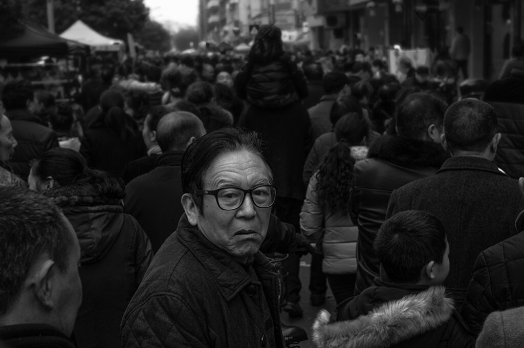 当地特有的民俗节日“保保节”迎来了20多万各地人来到这个小城，除了三大公园里进行热闹的“拉保保”的活动之外，城市里的主要干道也成了临时的集市，如潮的人们或逛或买，开心地享受节日带来的快乐，本是举起相机盲拍几张如潮的人流，无意中拍下了这回头一望的老人，类似的场景，似乎见过很多片子出现过。我也不知道老人为什么会是这样的表情，又在回望着什么。感觉不加以说明的话，会有各种的猜想吧。喜欢拍照，但是街拍我很盲目的，还请朋友们多多指点。