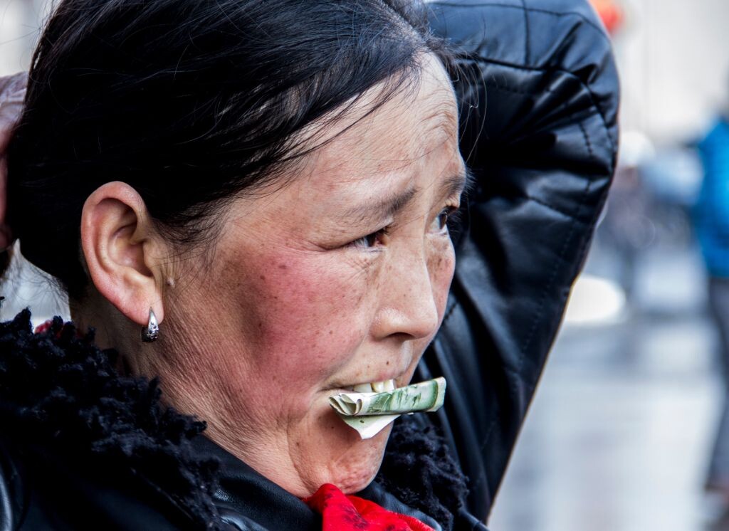 一个农民工大婶，嘴里咬着一张一元的人民币，没错，她也在等公交车，脸上一条条的皱纹是否就是她在这个城市打拼的写照，。。。。。。每个人的父母都不容易啊。。。
