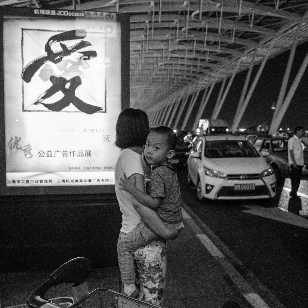 一身疲倦从机场出来,刚看到这对母子时就决心按下快门,恰好也遇到了合适的广告牌