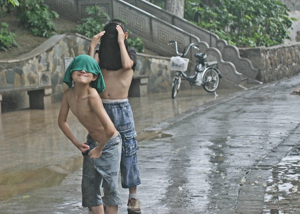 二个被雨淋湿了衣服，蒙头卖萌的男孩。      2011年7月摄于金狮河沿