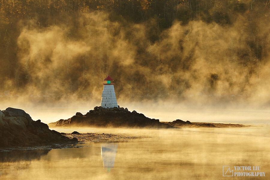 在哈利法克斯的一个清晨，雾气燃烧，灯塔在雾中挺立，倒影忽隐忽现。