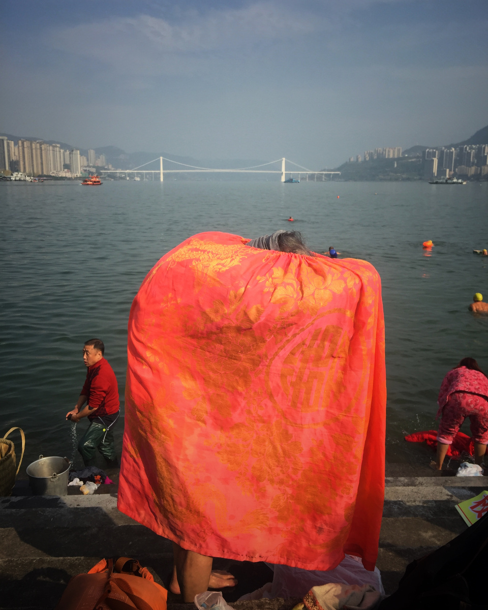 2016年12月1日,重庆万州万达广场外长江边,刚刚冬泳完的老奶奶在换