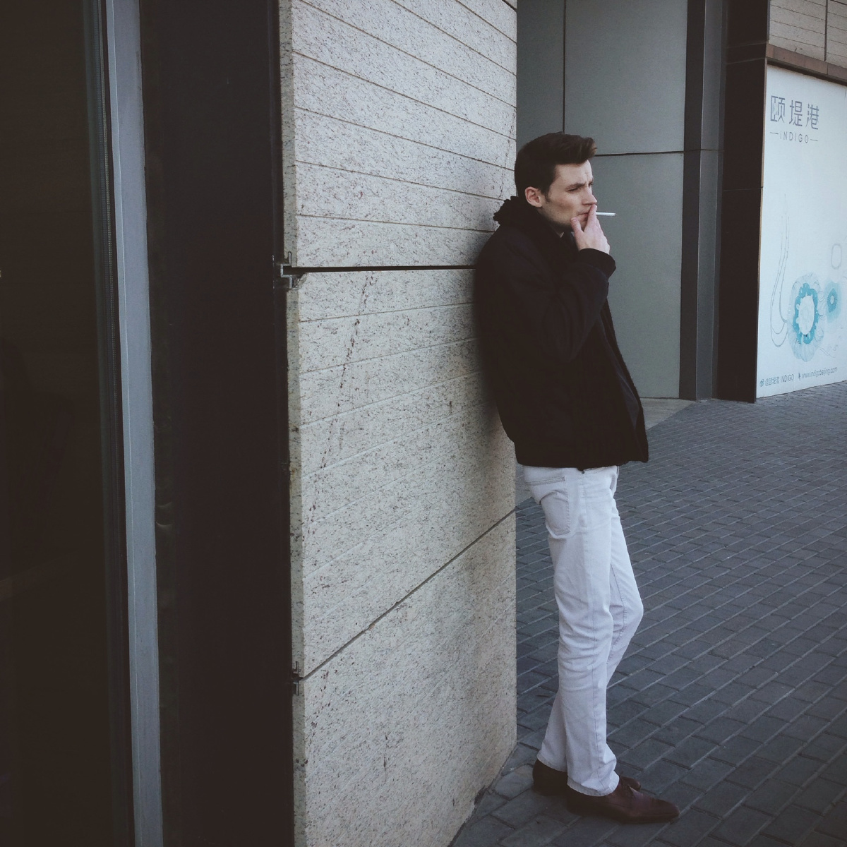 靠墙抽烟的外国男子