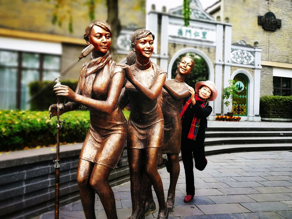 讴歌青春的活泼少女雕塑边,一个芳华犹存的退休女士,抓住活力四射少女