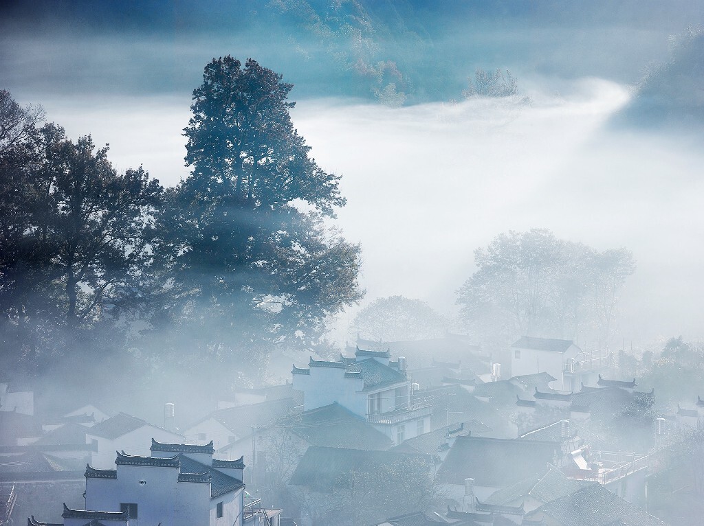 我使用300的长焦镜头来压缩空间和距离，将焦点落在白雾弥漫的徽派建筑上，画面雾气莽莽更为壮丽，山村虽小从而显得更加幽静，感官视觉上达成和谐。