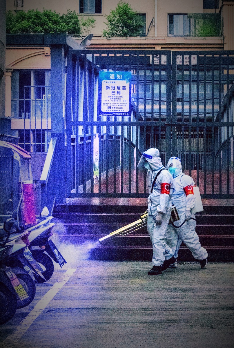 在抗疫一线的预备役民兵志愿者冒雨为社区消毒