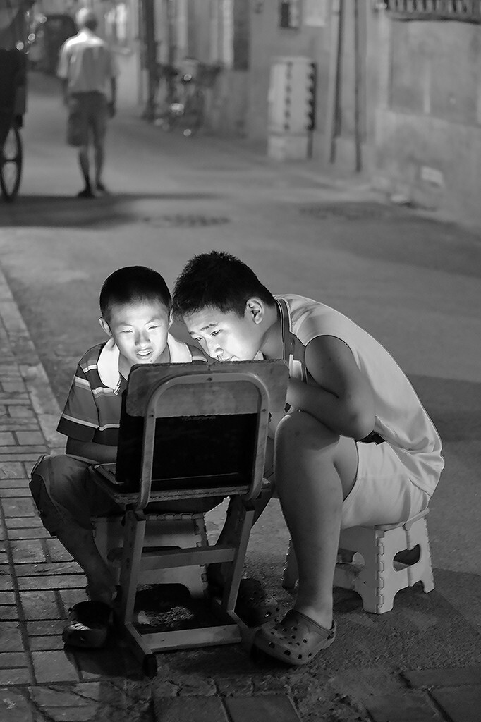 孩子们在街上玩电脑，旁若无人，仿佛在自家客厅。