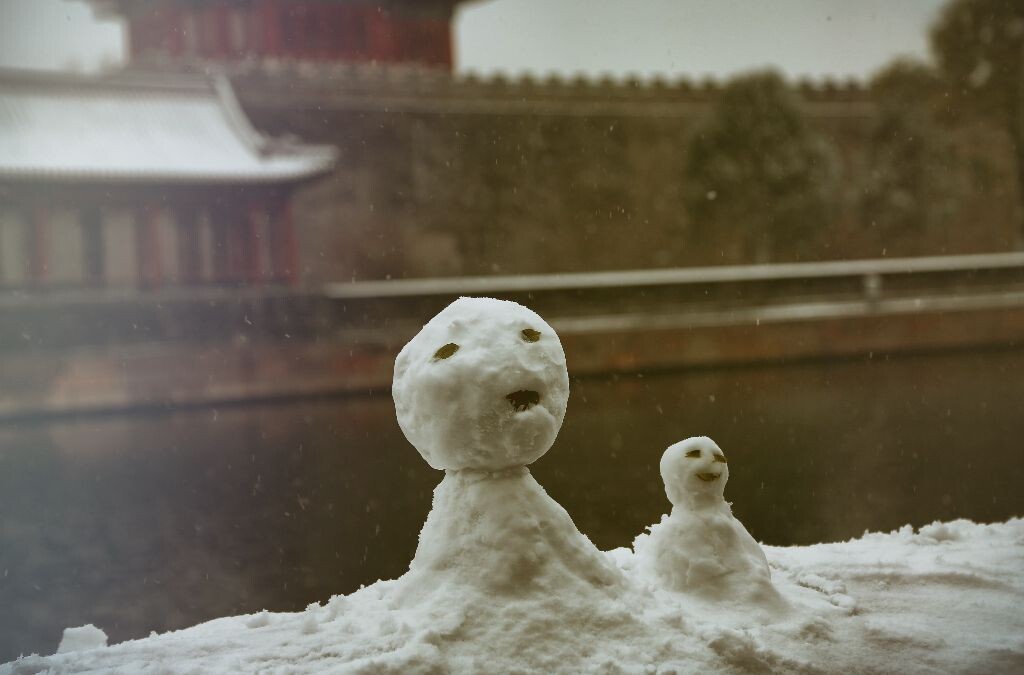 童真童趣的人们在围墙上堆起了各种小雪人