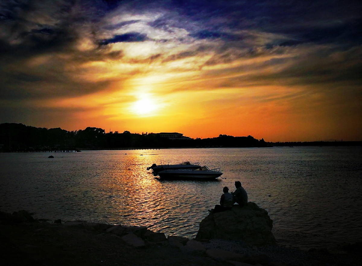 大海边一对恋人依偎在一起观赏夕阳美景