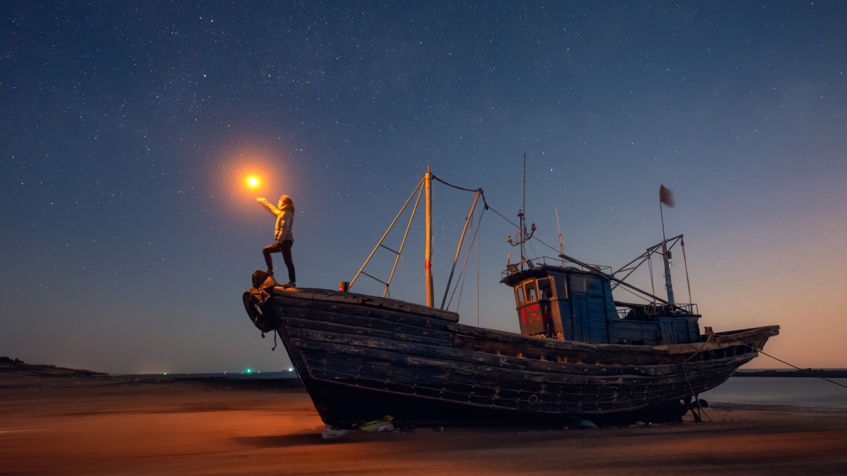 月亮升起将整个夜空照亮前景找了一艘渔船拍下了这张星空下的渔船照片