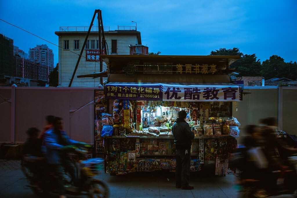 机器轰鸣,尘土满天的工地与人来人往的市井仅仅一墙之隔。流动的人群似乎象征着无论城市经历着怎样的变迁,生活依然向前不止息。