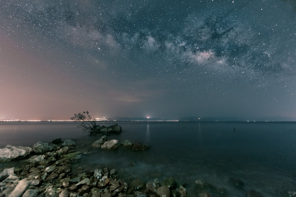 涨潮，前景的卵石滩，丝滑般的湖水，小树，银河。前景用iPhone闪光灯补光，单张出片。
