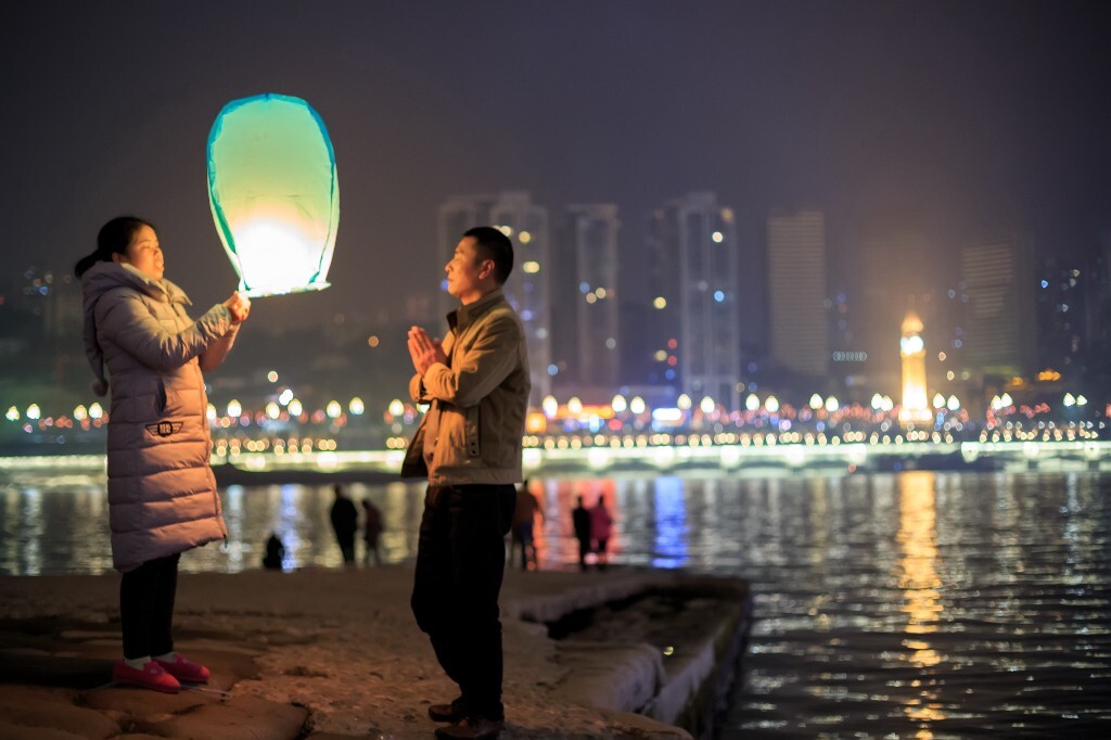 元宵节重庆江北嘴江边，一家正在放孔明灯，这家的父亲不断的在为家里人祈福。