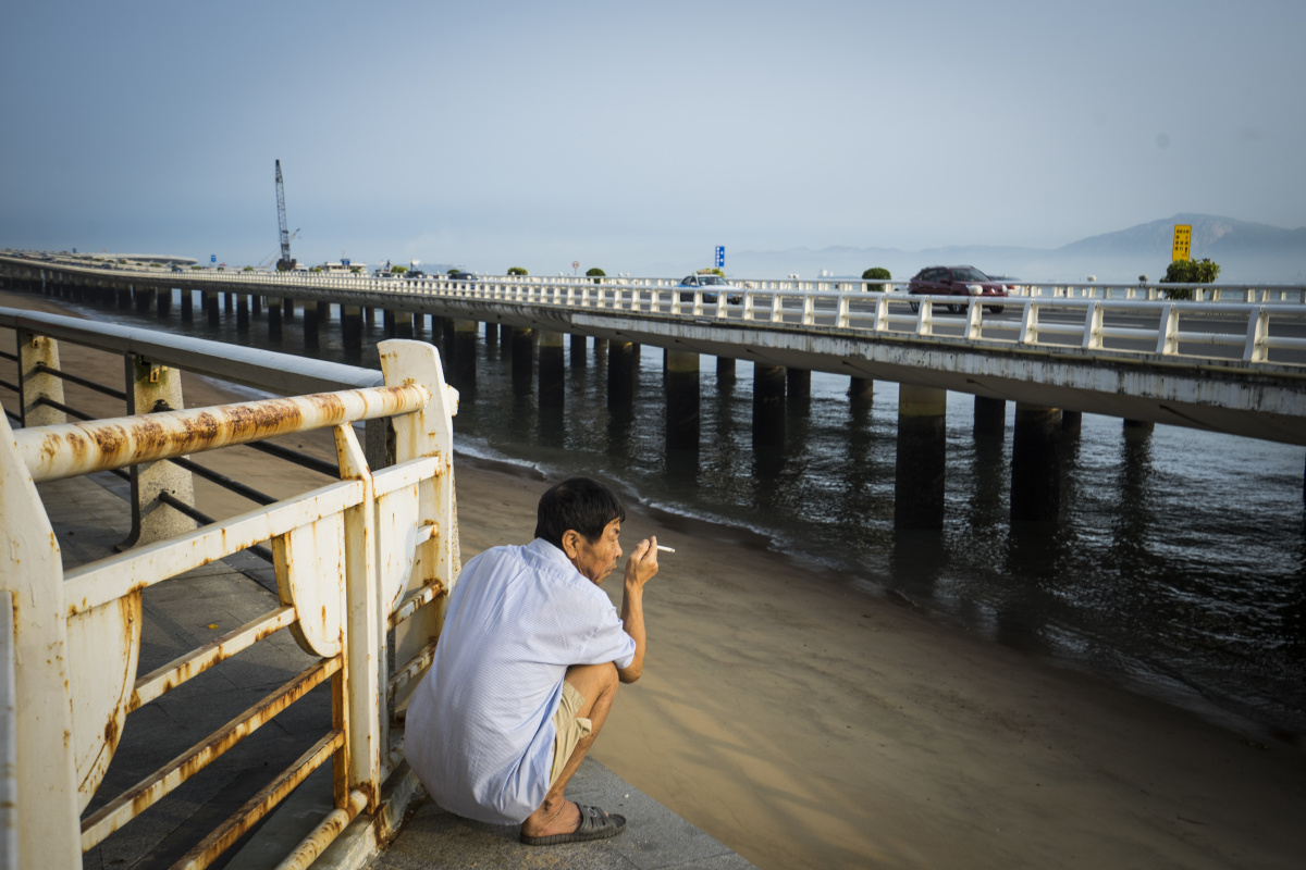 蹲在护栏外抽烟的中年人.2016年,沙坡尾避风坞外.