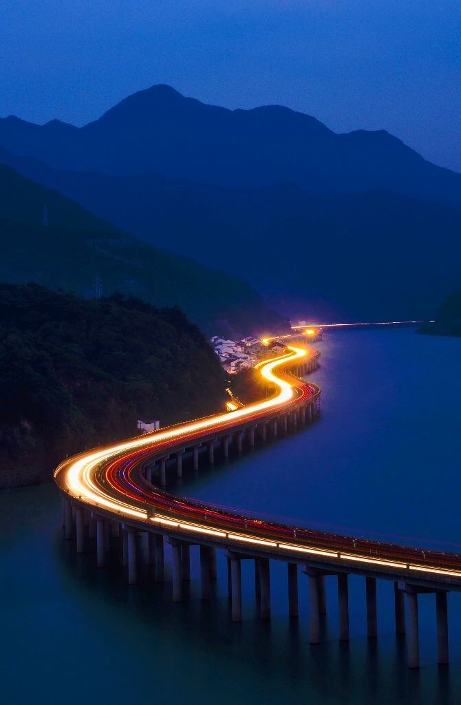 夜幕降临，沿江而卧的高速公路被穿流车灯拉出长长轨迹，似一条七彩蛟龙腾空飞舞。