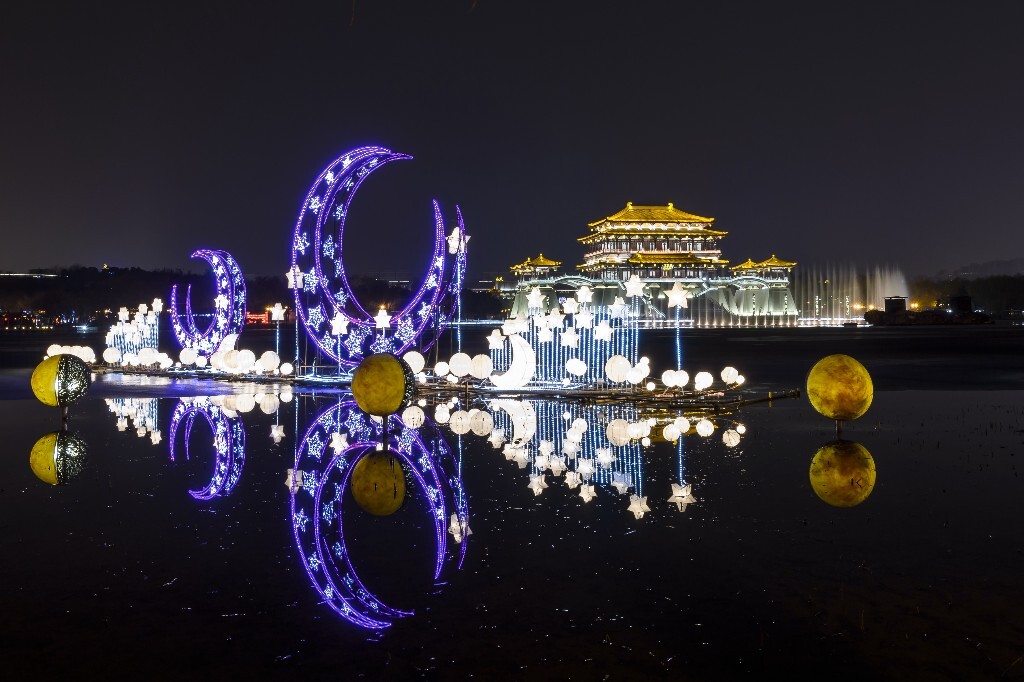 大唐芙蓉园内，以星月为主题的彩灯漂浮在静谧的湖面上，衬托着远处高耸屹立的紫云阁，显得庄严而神秘。