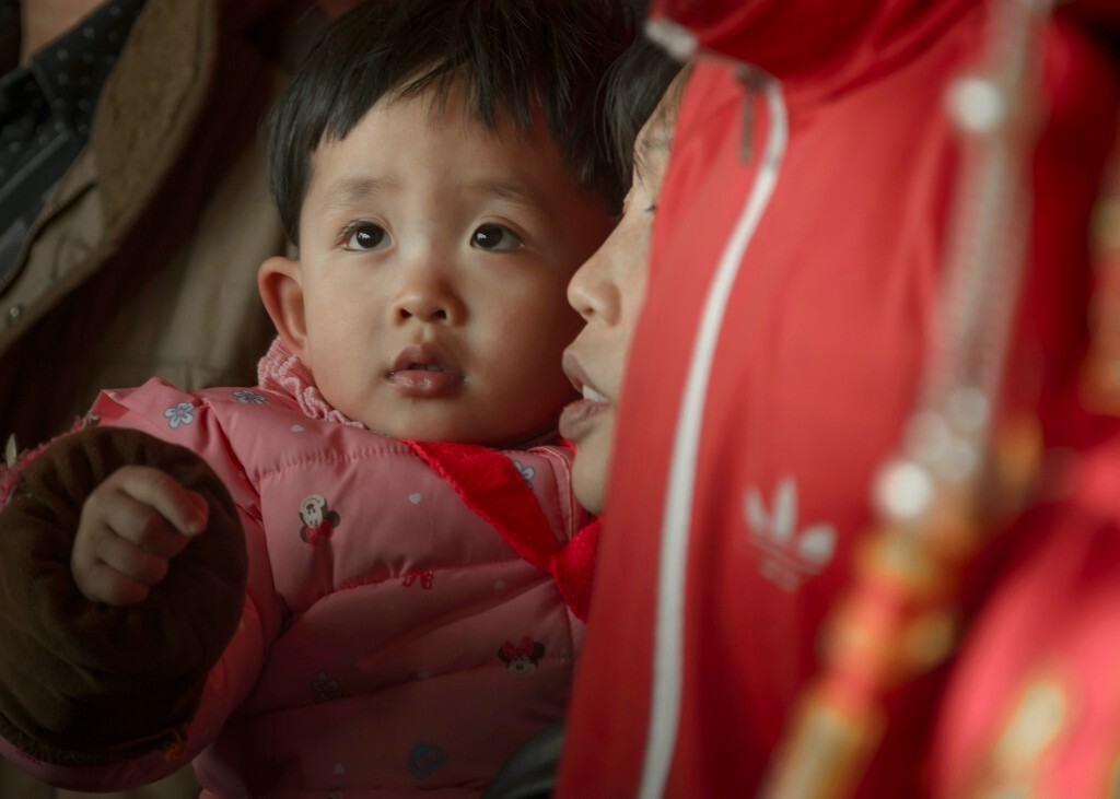 在母亲怀抱观看仪式的婴儿。