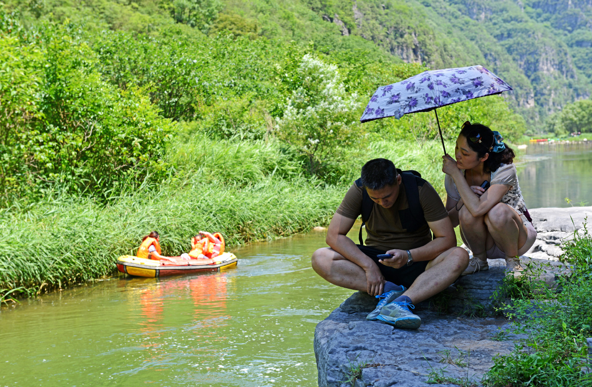 这是在旅游景区休息时的一对夫妻,一把遮阳伞带来了爱 的阴凉