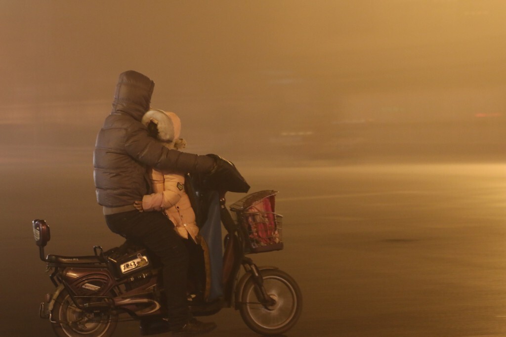20151223，秦皇岛，21:00，重度雾霾，空气质量指数242，在一个十字路口，一位骑电动车的父亲，让女儿趴在自己胸前。原创，拒绝后期制作。
