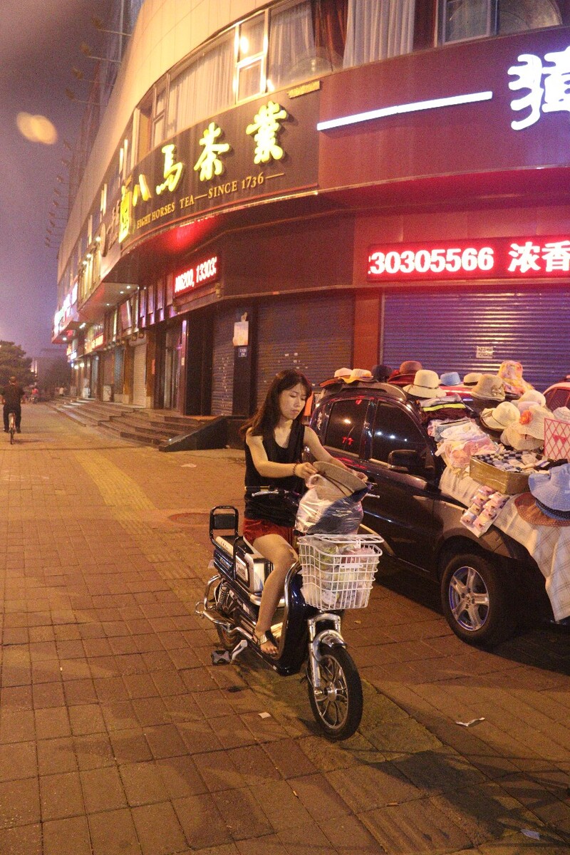 实时空气质量指数179,中度污染。一位没有任何防护的女孩在街边刚买了一顶草帽。