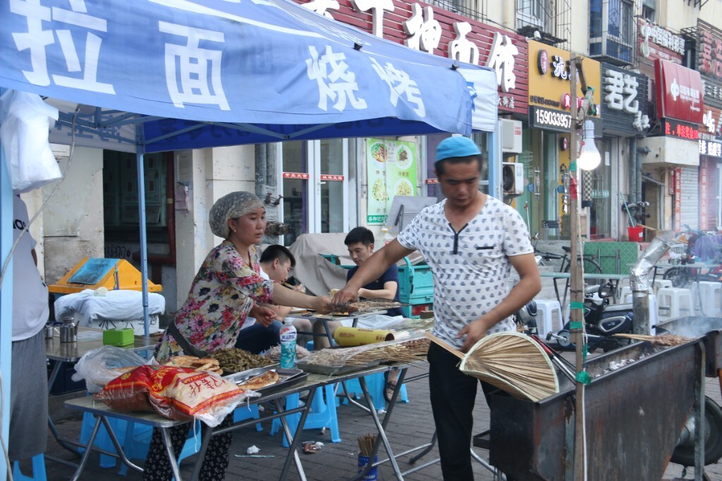 实时空气质量指数185,中度污染。雾霾下拉面馆门前和往常一样摆起了露天烧烤,客人们已经陆续的来了。