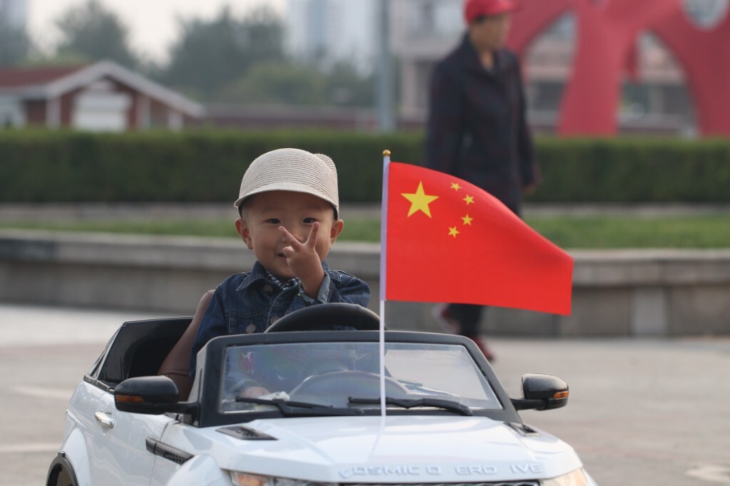 国庆假期的一个傍晚，去广场上溜达，偶遇一位开着电瓶车的小朋友，他的小电瓶车上的五星红旗格外鲜艳。原创。拒绝后期制作。