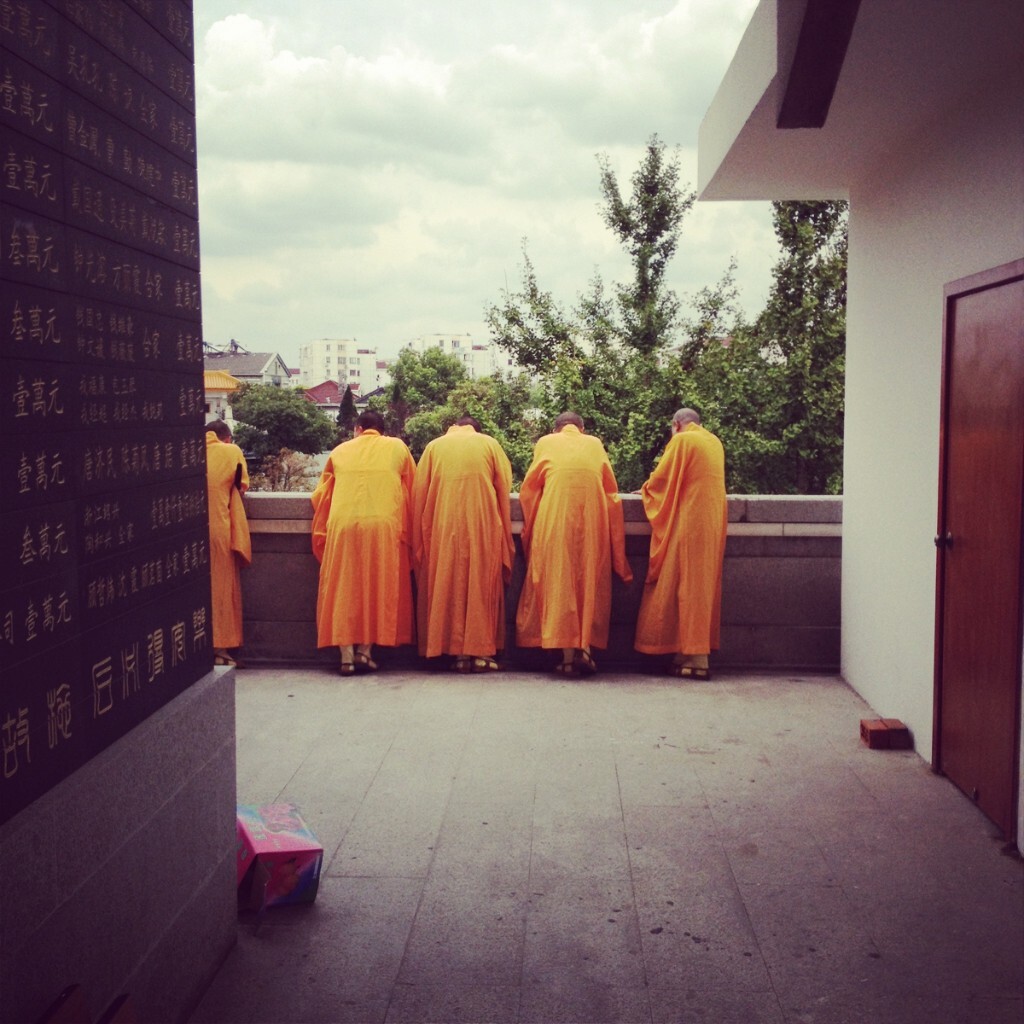 上海七宝寺里的和尚们看着墙下马路行人消磨时光，可能是开饭时间还早所以大家唠一会嗑，增进一下感情。