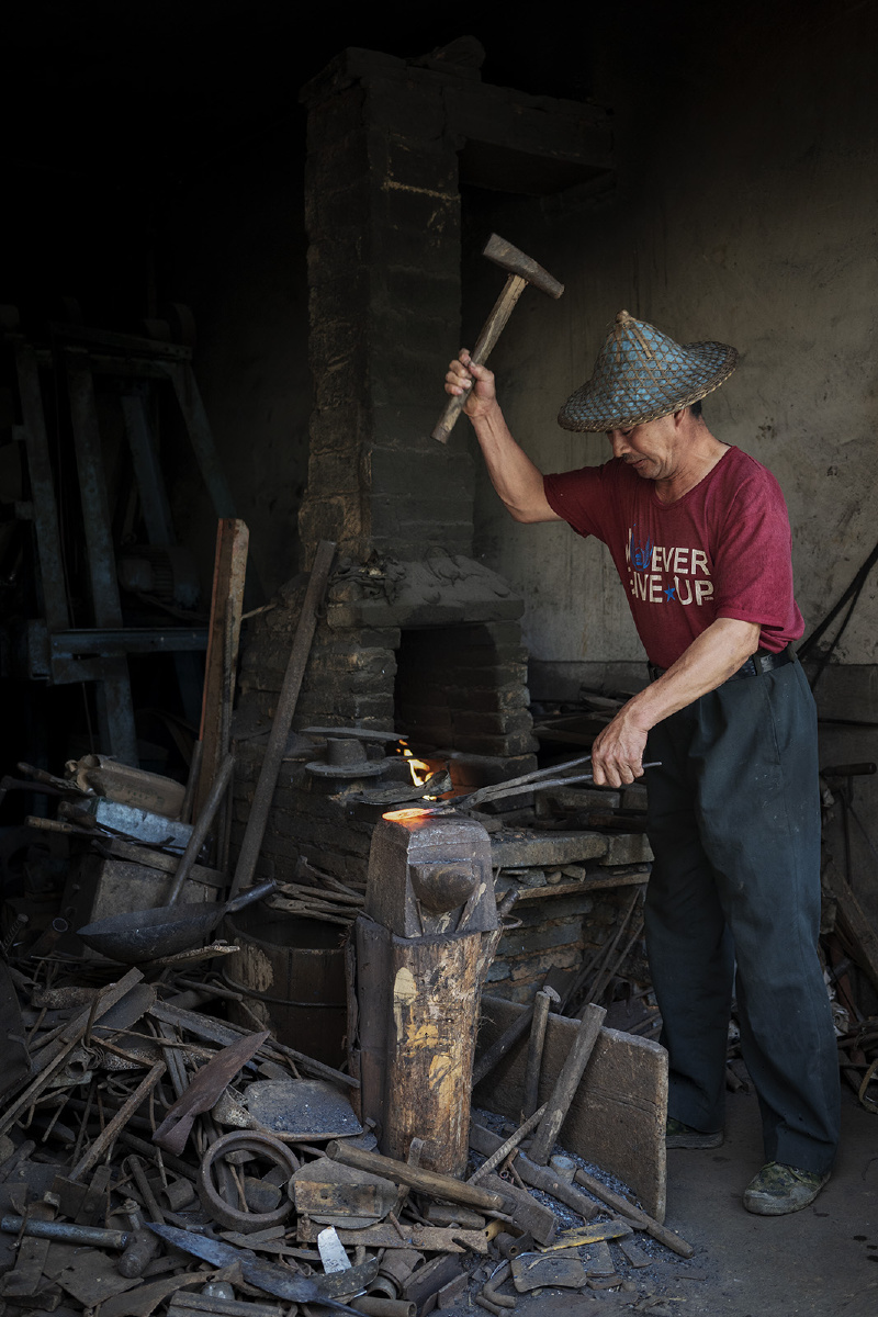 武夷山下梅村的老铁匠铺午休后铁匠师傅拉起风箱烧红铁块抡锤锻打如此
