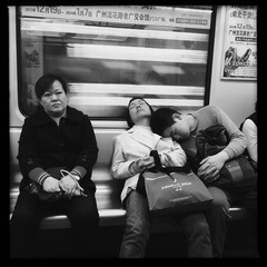 2013年12月3日，广州五号线地铁车厢内，青年靠在大人的肩膀上睡着了。