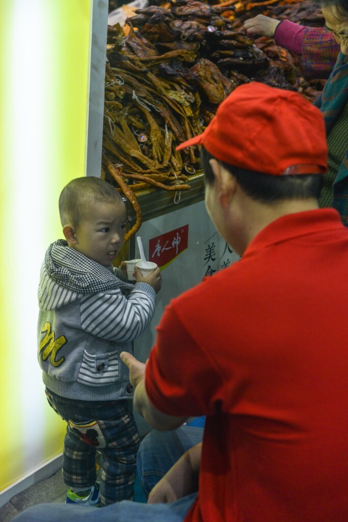 2015年长沙农博会上，在经过一个展位时候。一个孩子在柜台边，躲避到一边。你想想这个叔叔说什么了？这个孩子这个表情。此刻你会知道孩子想说什么？