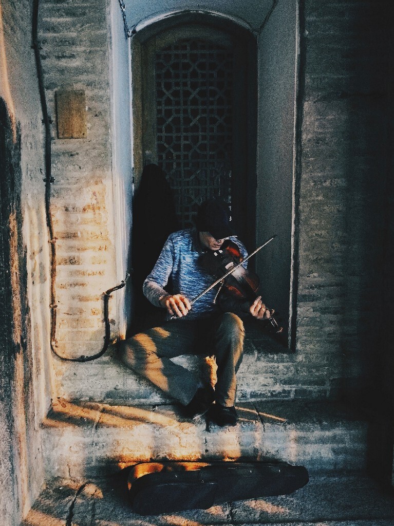 伊朗伊斯法罕，我们在大拱门下走着，突然传来一阵悦耳的小提琴声，跑去看，是一个街头表演的艺人，悠扬的琴声顿时引来很多人的关注，旁边的清真寺显得格外宁静和神圣。