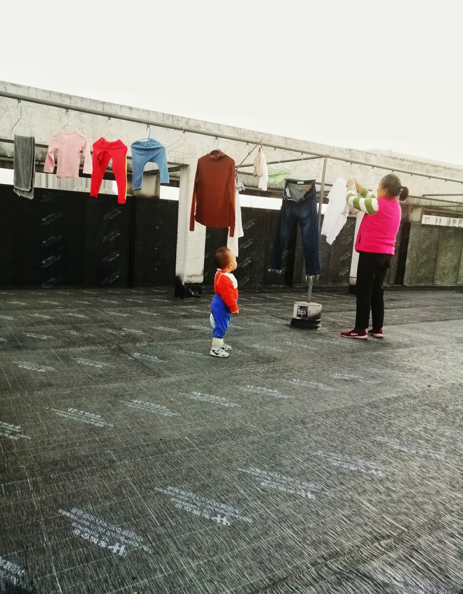 工厂宿舍楼顶奶奶带着小孙女收晾晒的衣服