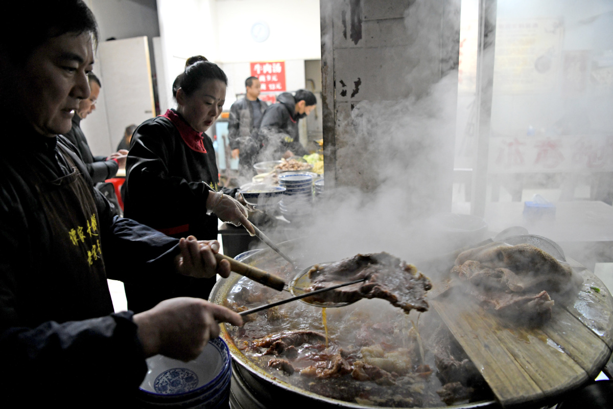 谭业镇与妻子赵雪芹煮好一大锅新鲜牛肉汤满足市民对地方特色美味早餐